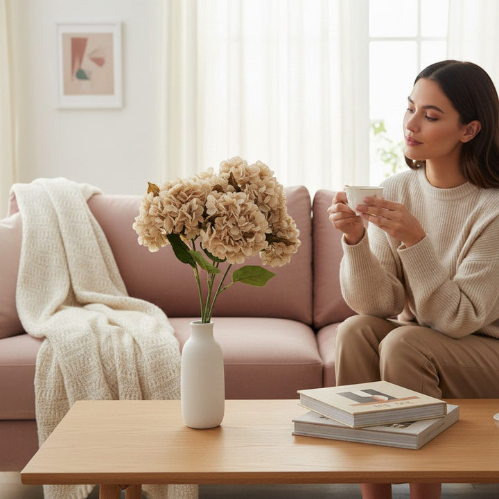 Chic Collective 24" beige artificial hydrangea spray in a white vase on a coffee table.