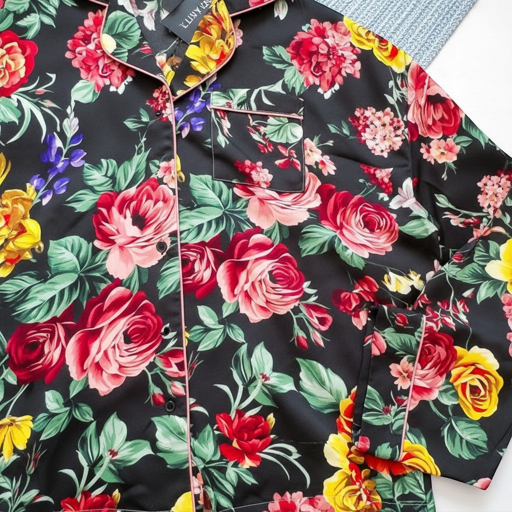 Chic Collective black satin pajama set with a vibrant floral print featuring roses, peonies, and accent flowers. Pink piping details.