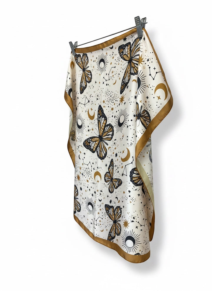 Chic Collective ivory satin scarf with monarch butterflies, moons, suns, and stars. Caramel border.