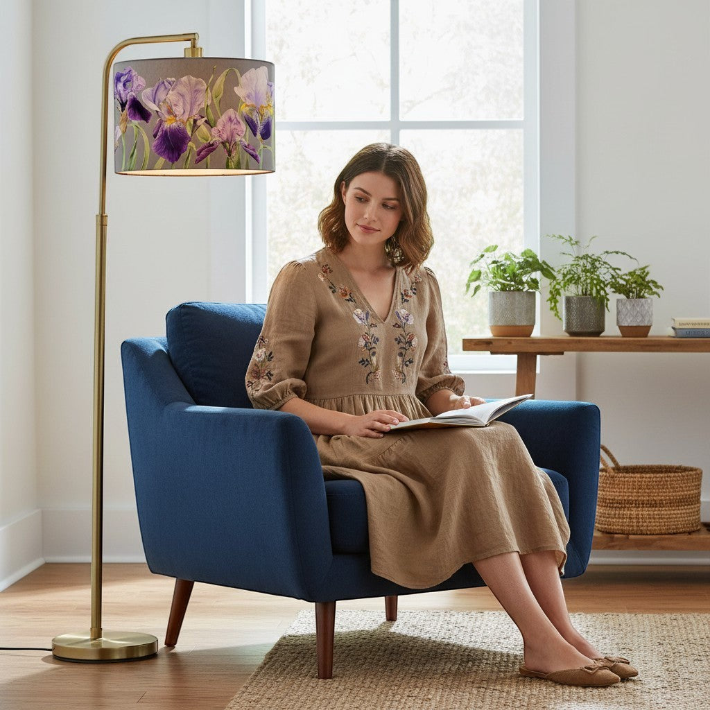 Chic Collective Elva Eva lampshade with purple iris watercolour design on natural fabric, a woman sits in a blue armchair reading.