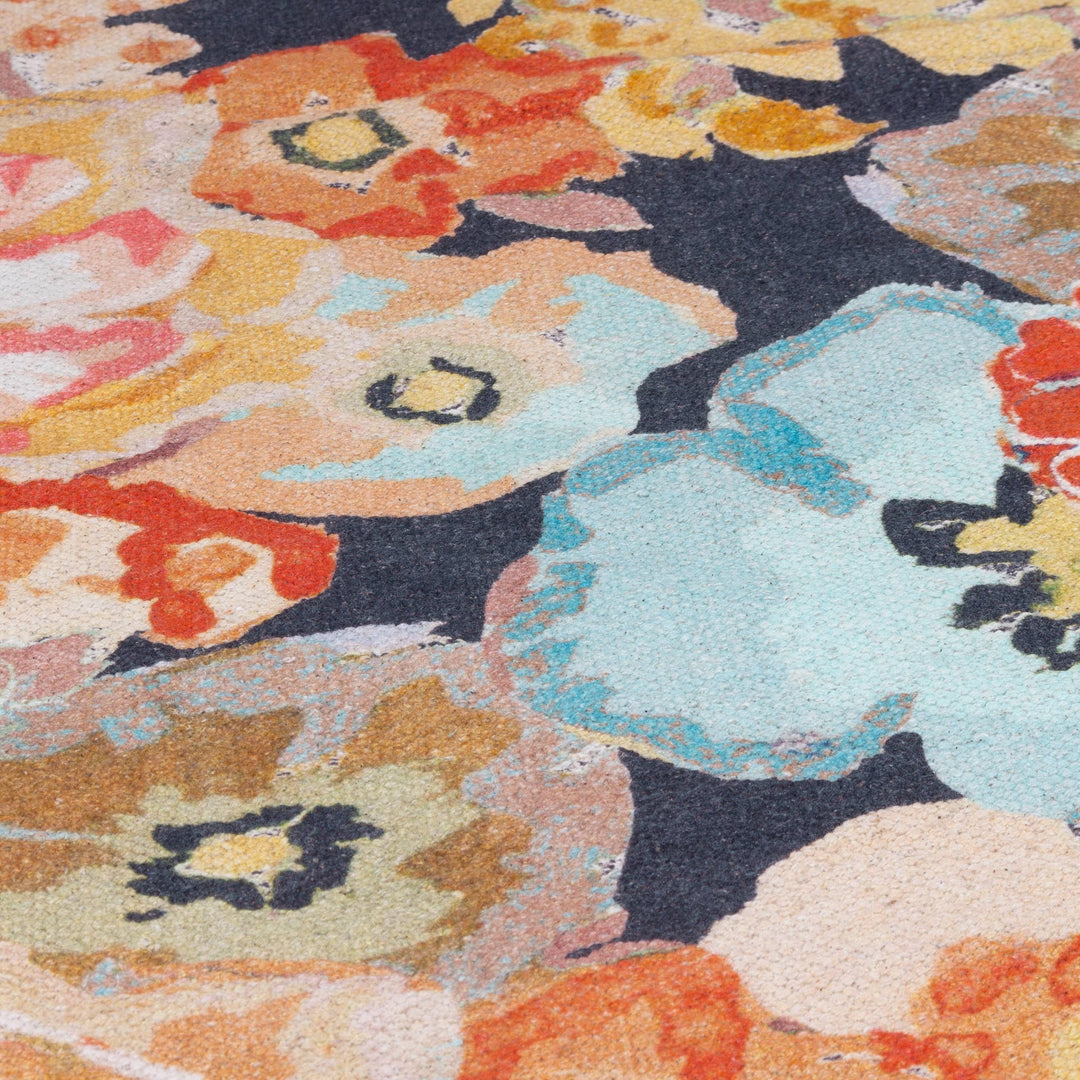 Chic Collective Florage 120x180cm rug with a peach, blue, and orange floral print on a dark background. Made of woven cotton.