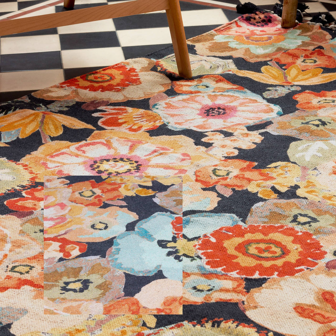 Chic Collective Florage 120x180cm rug with a vibrant floral print on woven cotton. Features peach, orange, and blue flowers on a dark background.