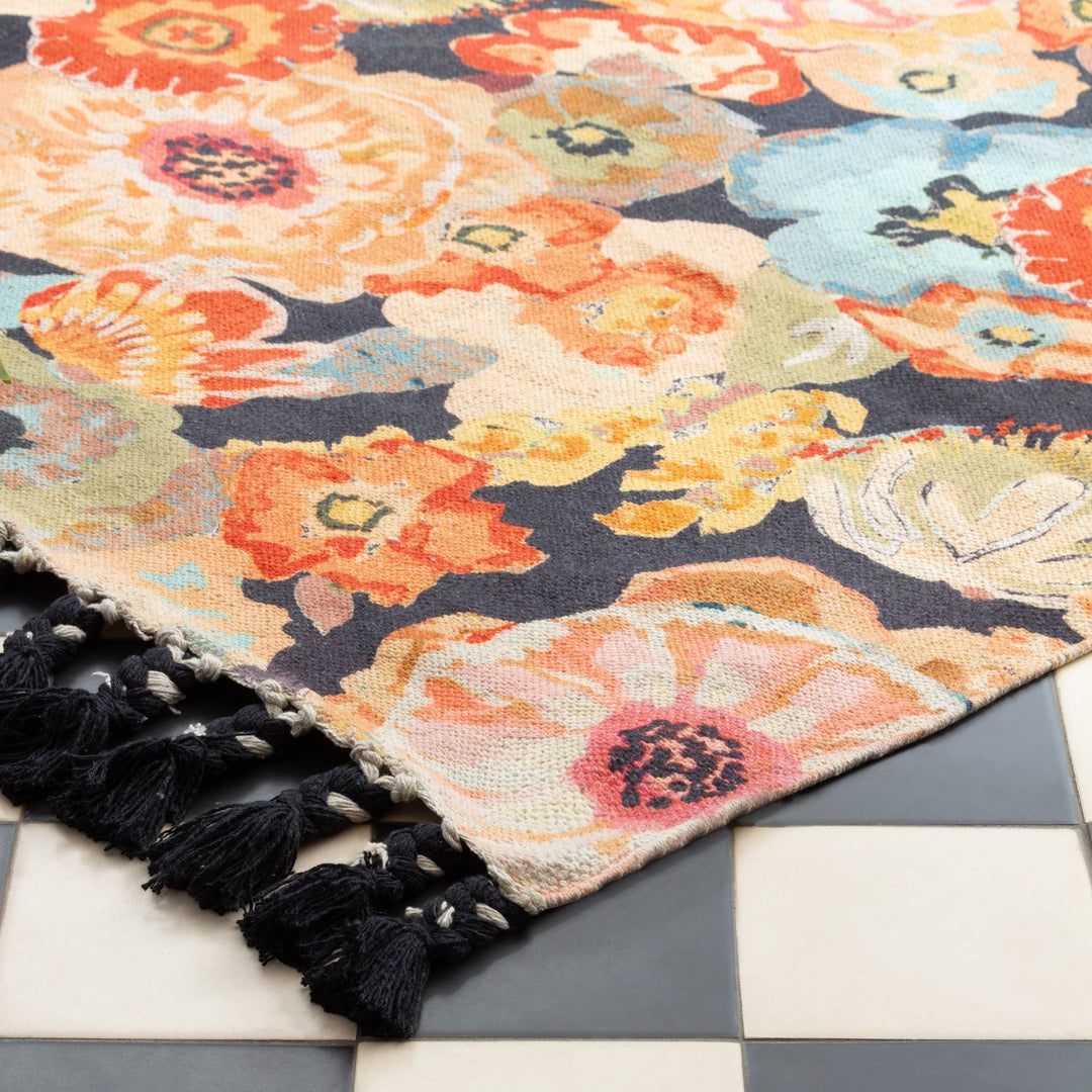Chic Collective Florage 120x180cm rug with a vibrant floral print in peach, orange, and blue hues on a dark background. Features braided tassel trim.