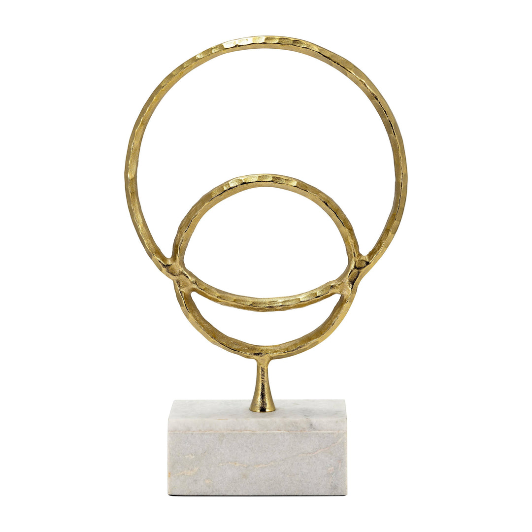 Chic Collective gold metal double ring sculpture with hammered texture on a white marble base.