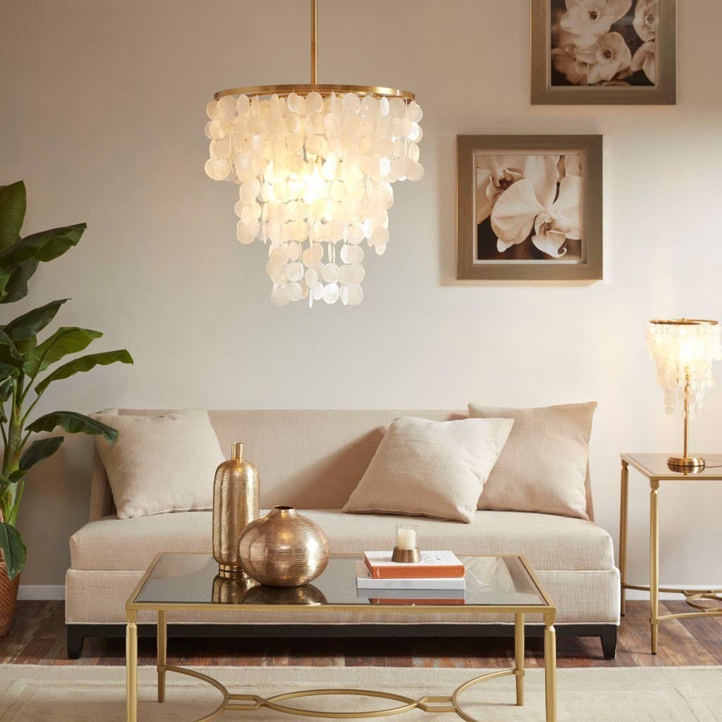 Chic Collective elegant chandelier with gold base and white shell-shaped tiers, illuminating a living room.