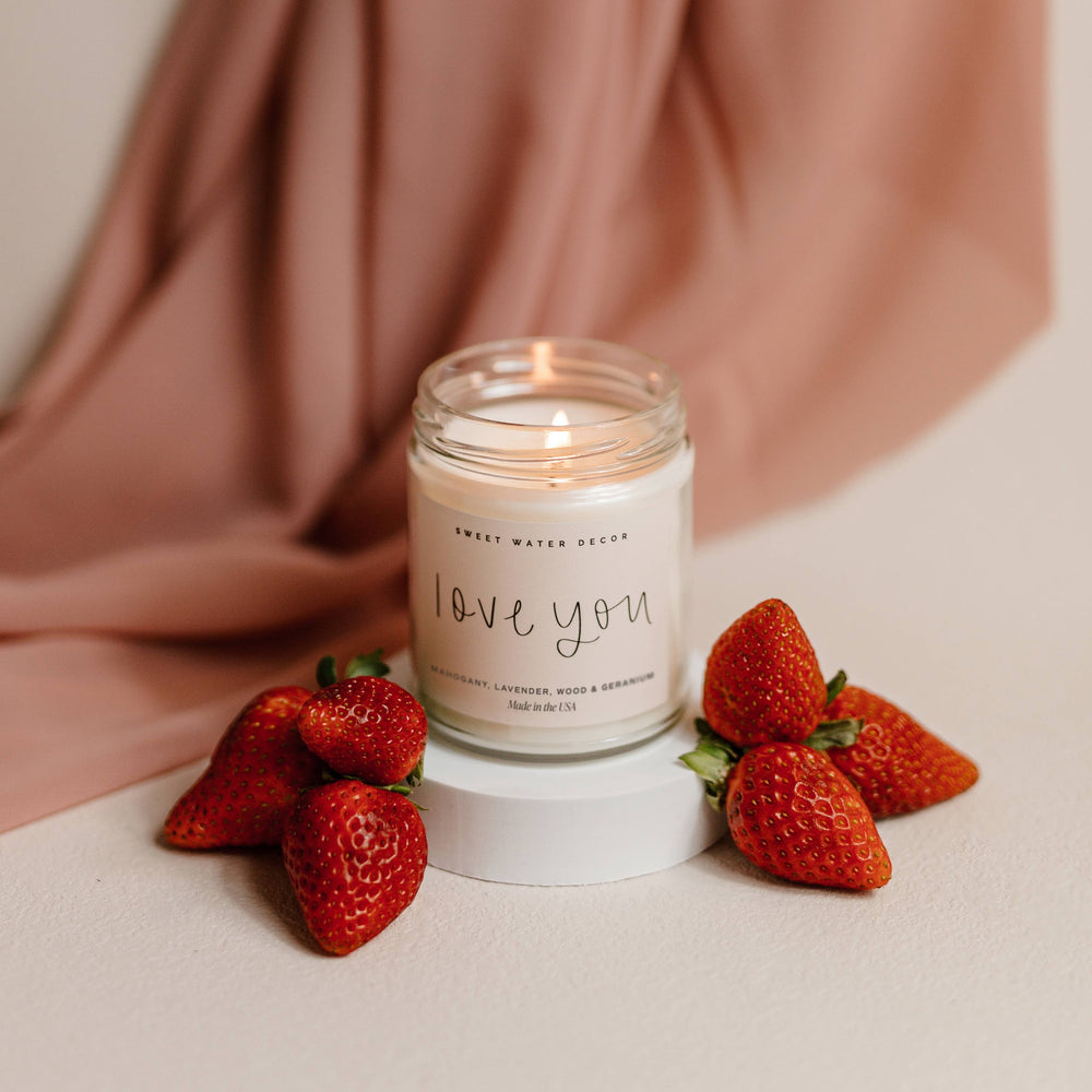 Chic Collective Love You 9 oz soy candle with driftwood and mahogany scent, surrounded by fresh strawberries.