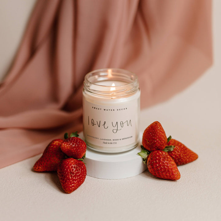 Chic Collective Love You 9 oz soy candle with driftwood and mahogany scent, surrounded by fresh strawberries.