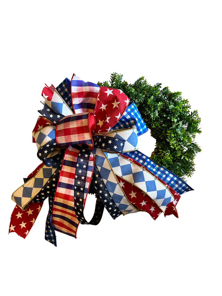 Chic Collective patriotic bow with red, white, and blue stars, stripes, gingham, and diamonds on a wreath.
