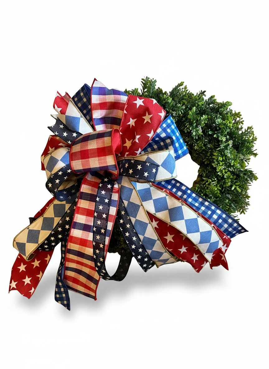 Chic Collective patriotic decorative bow with red, white, and blue patterns including stars, stripes, and gingham on a green wreath.