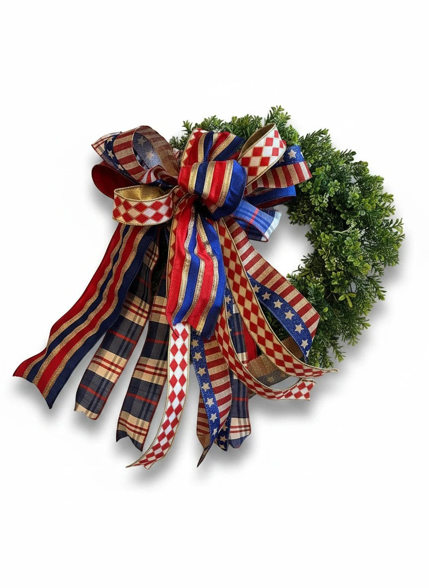 Chic Collective patriotic bow with red, white, and blue ribbons featuring stars and plaid patterns, attached to a green wreath.