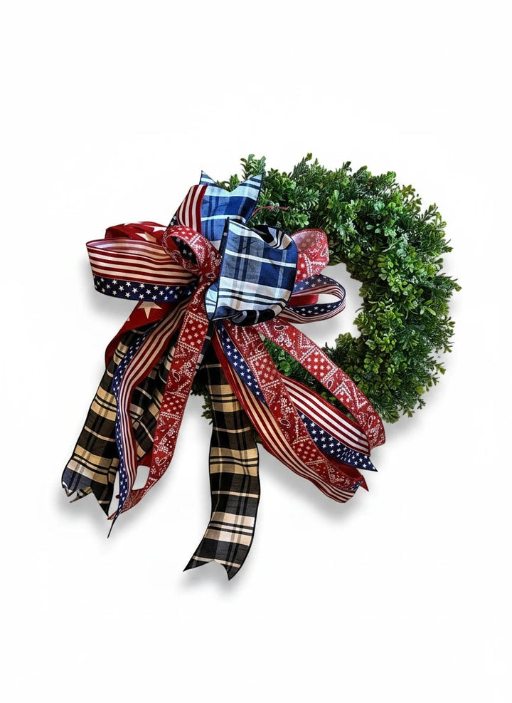 Chic Collective patriotic bow with red, white, and blue ribbons featuring stars and plaid patterns, attached to a green wreath.