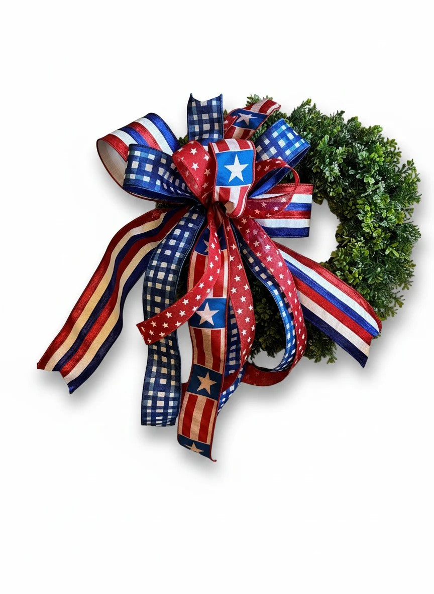 Chic Collective patriotic bow with red, white, and blue ribbons featuring stars and stripes patterns on a green wreath.