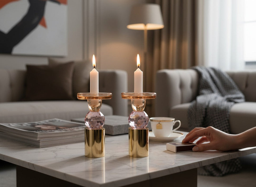 Chic Collective set of 2 pink and amber crystal candlesticks, 6.5"H, with gold bases, on a marble table.