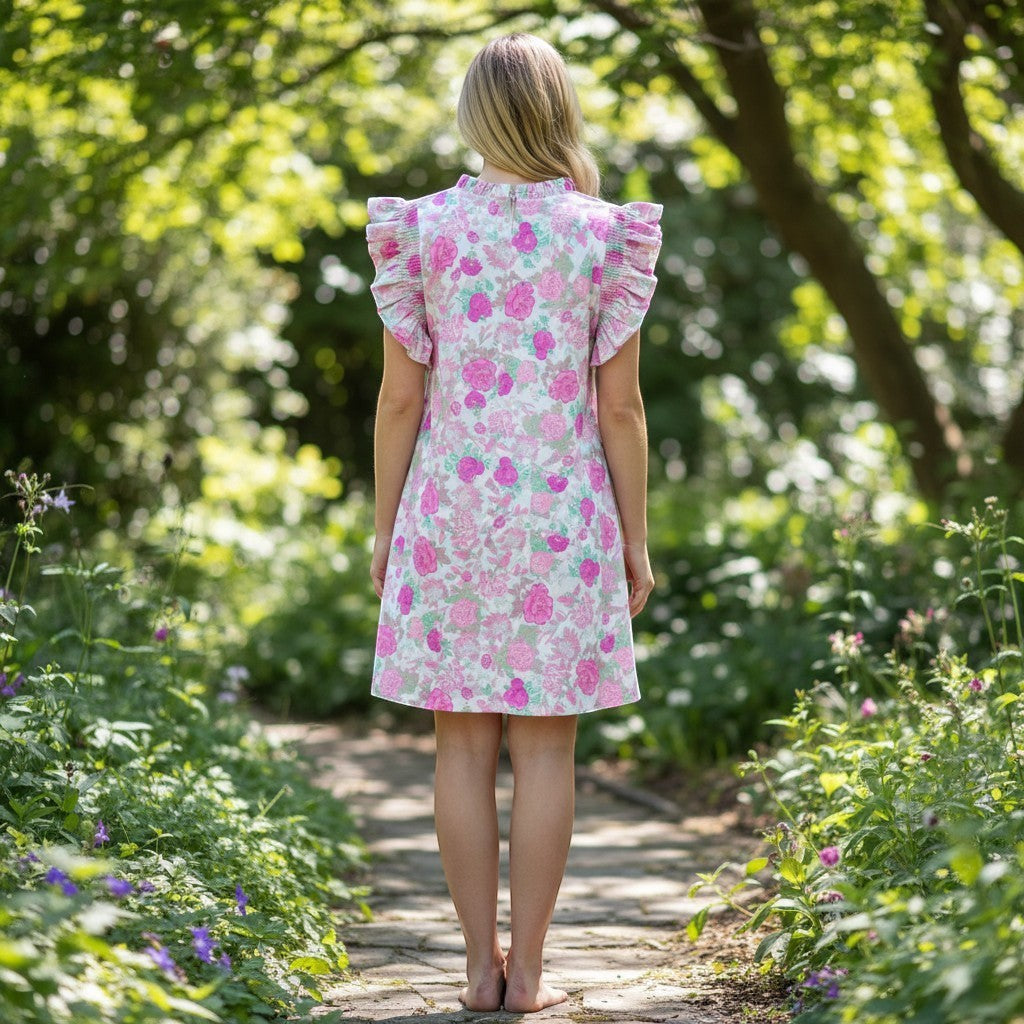 Chic Collective pink floral dress with ruffled sleeves and a high neckline, worn by a woman standing in a garden.