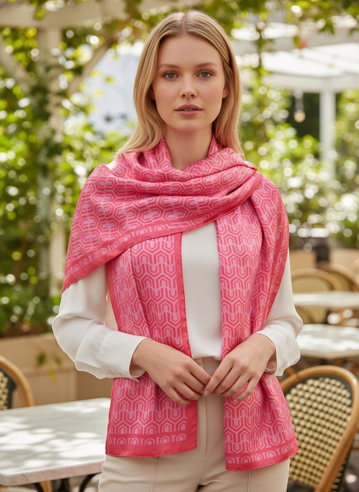Chic Collective pink geometric pattern satin scarf with a glossy finish, worn by a woman outdoors.