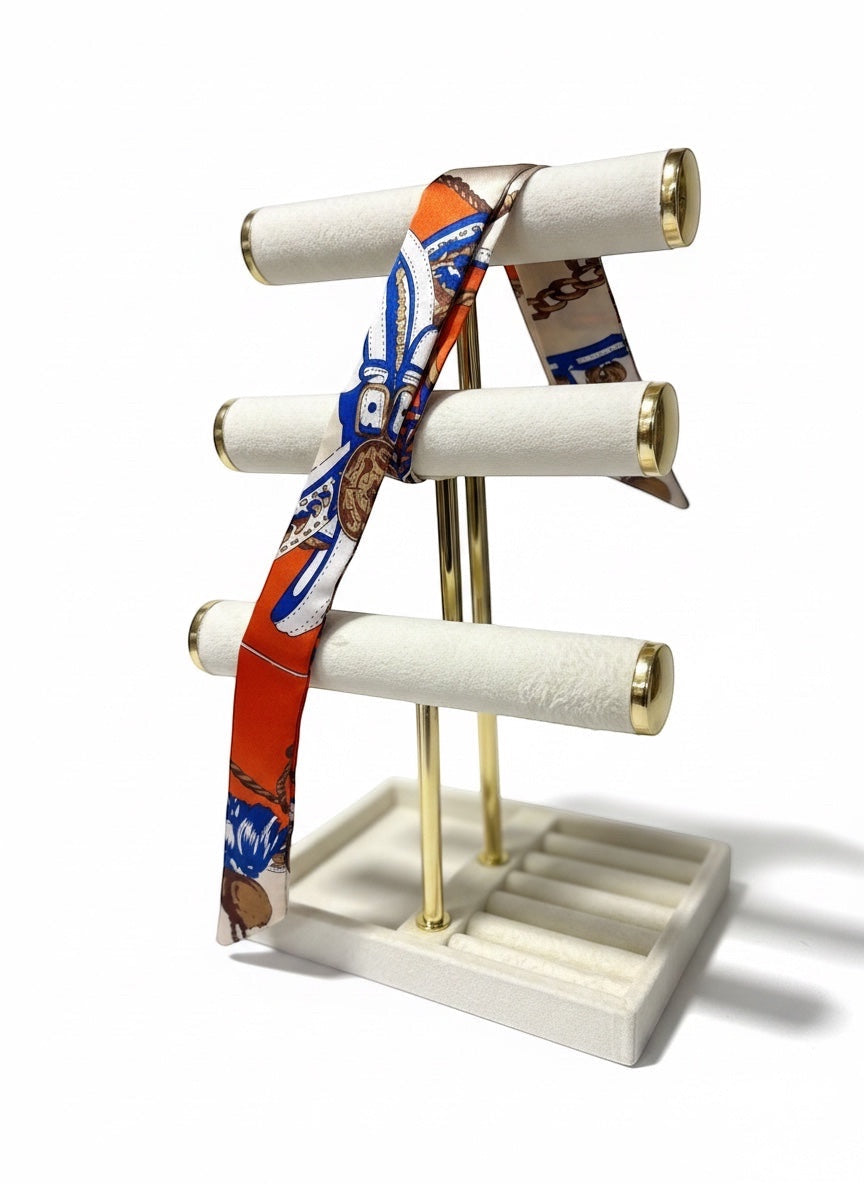 Chic Collective Riviera Luxe Ribbon Tie, a silky scarf with orange, blue, ivory, and equestrian print, styled on a jewelry stand.