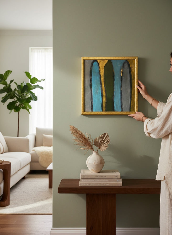 Chic Collective Sacred Passage abstract painting with teal, olive green, and grey vertical forms on gold background, framed in antique gold.