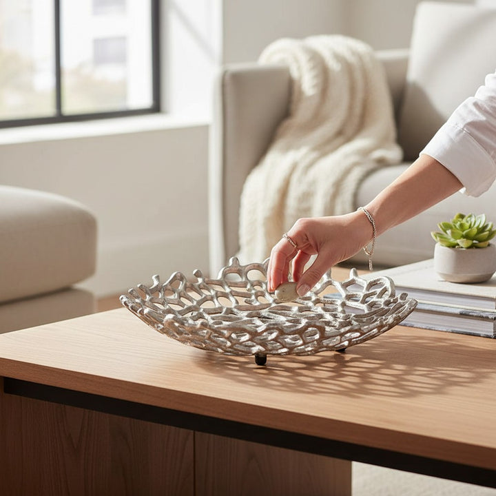 Chic Collective silver aluminum coral decorative bowl with intricate cutout design, placed on a wooden coffee table.