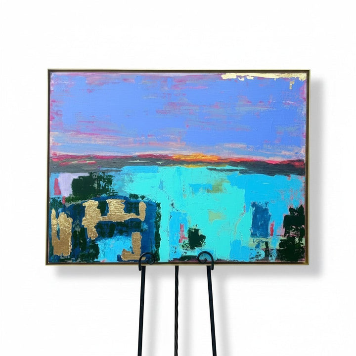 Chic Collective abstract landscape painting with vibrant blues, pinks, and gold leaf accents. Depicts a sunset over water.
