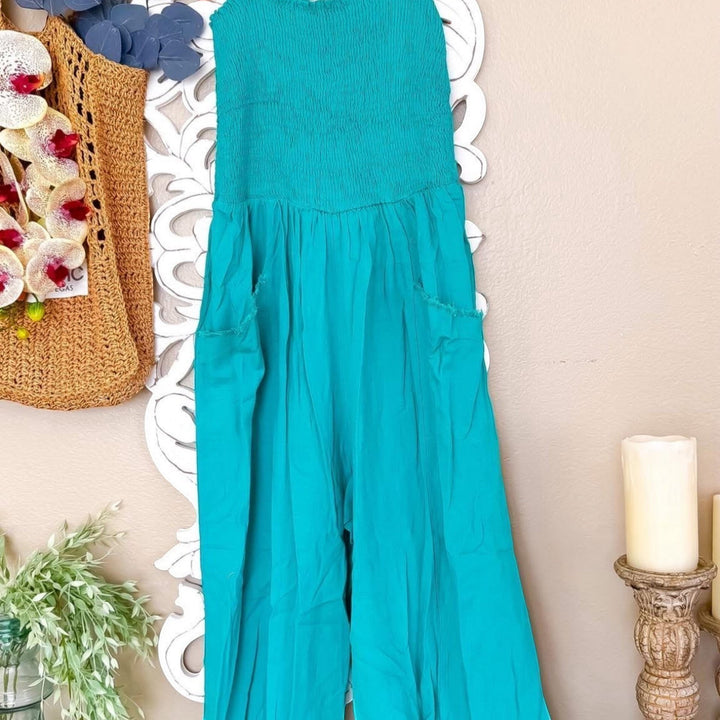 Chic Collective teal strapless jumpsuit with smocked bodice and wide legs, featuring two front pockets.