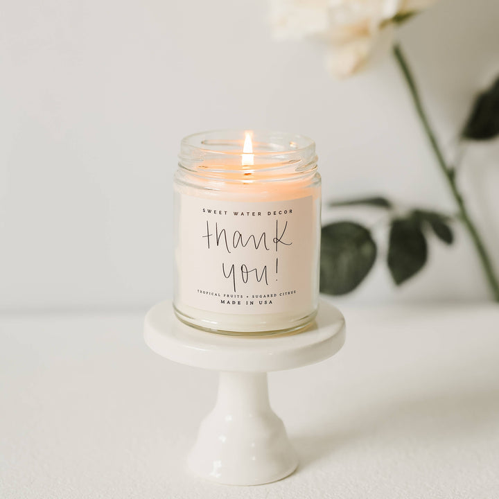 Chic Collective 9 oz soy candle in a clear jar with a cream label that says "thank you!" with tropical fruits and sugared citrus notes.