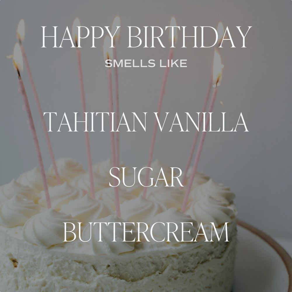 Chic Collective Happy Birthday vanilla buttercream soy candle with pink birthday candles on a white frosted cake.
