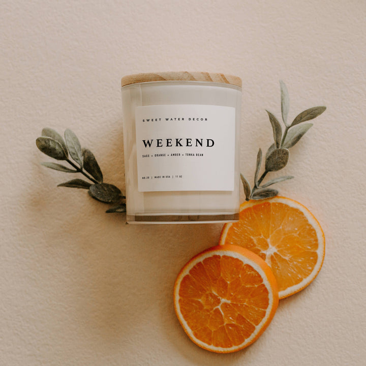 Chic Collective Weekend 11 oz soy candle in a clear glass jar with a wooden lid, featuring citrus, grapefruit, sage, lavender, amber, tonka bean, and oakmoss scents.