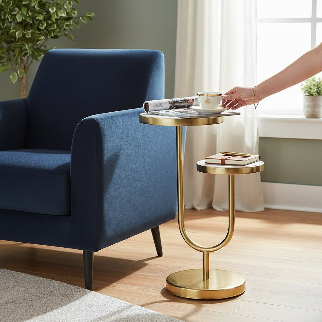 Chic Collective two-tier round end table with white marble tops and gold iron base, next to a blue armchair.