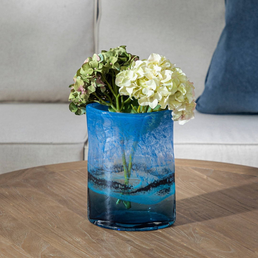 Chic Collective Alaborg hand-blown cobalt blue glass vase with swirling aqua and black accents, holding hydrangeas.