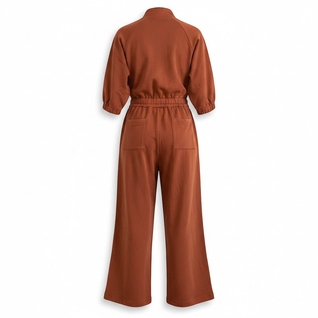 Chic Collective brown cotton jumpsuit with elasticated waist, wide legs, and patch pockets. Mock neck and puffed sleeves.
