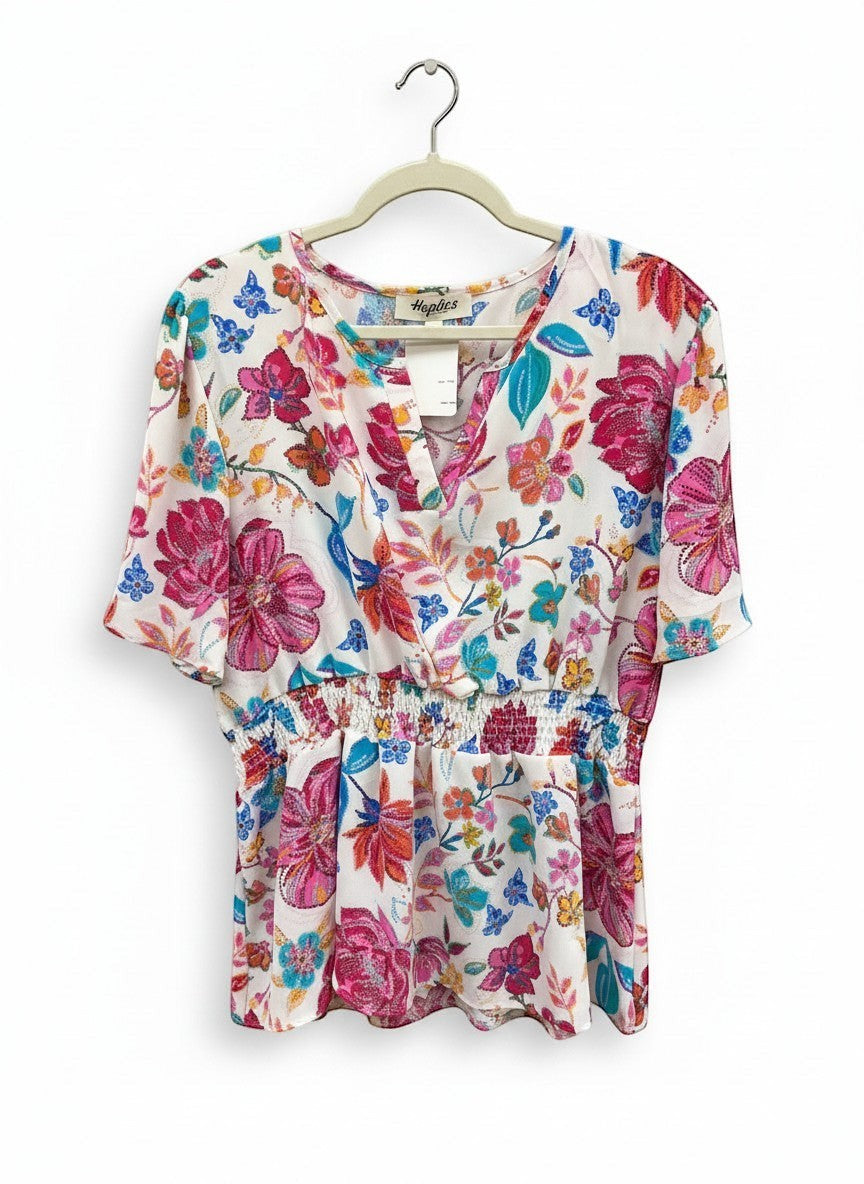 Chic Collective floral print blouse in ivory with hot pink and blue flowers, featuring a V-neck and smocked waist.