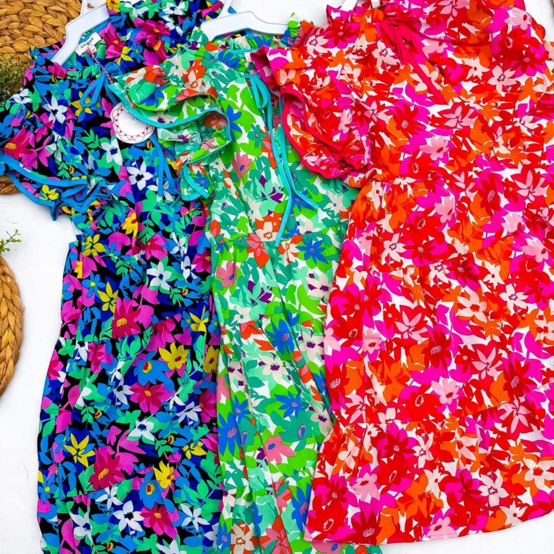 Chic Collective vibrant floral print dresses in green, blue, and red. Short sleeves, tiered skirt, and ruffled neckline.