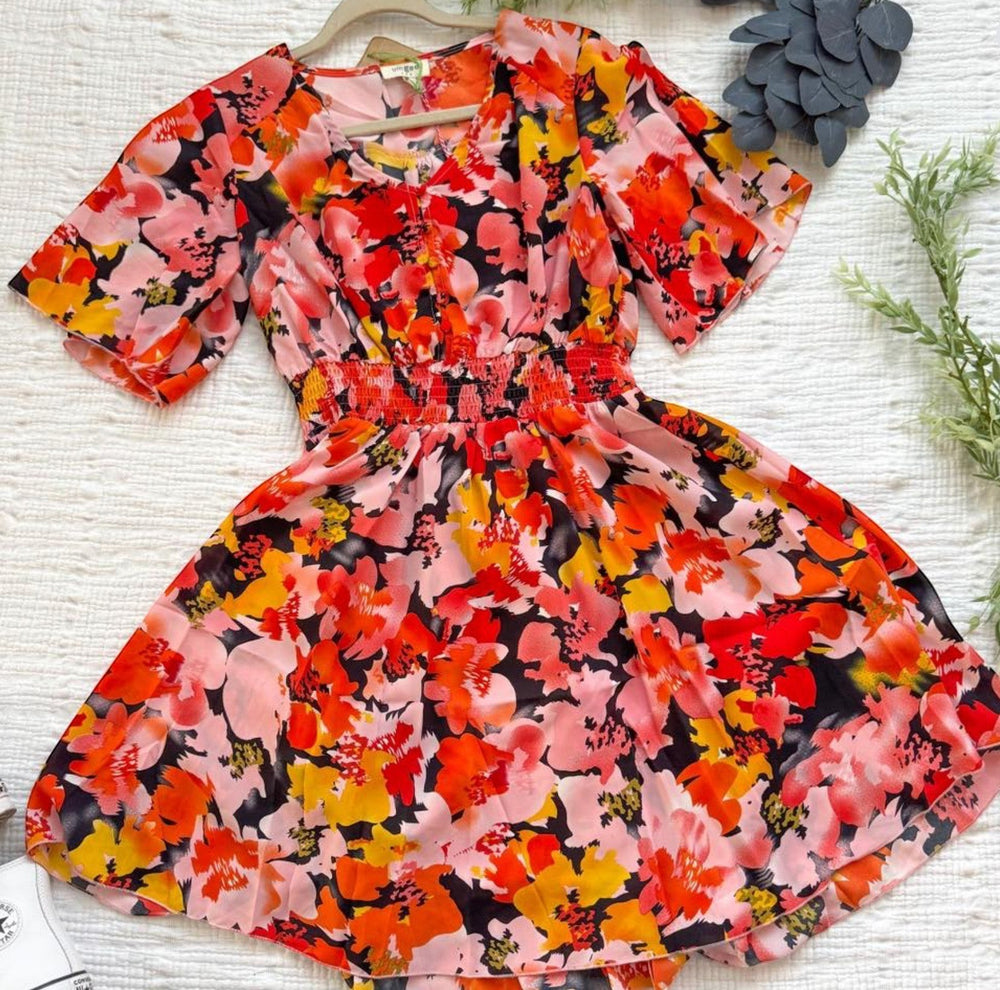 Chic Collective pink, peach, orange, yellow, and black floral print V-neck short sleeve smocked waist mini dress.