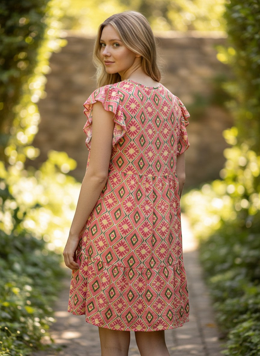 Chic Collective coral, yellow, and green geometric print tiered ruffle sleeve dress on a woman outdoors.