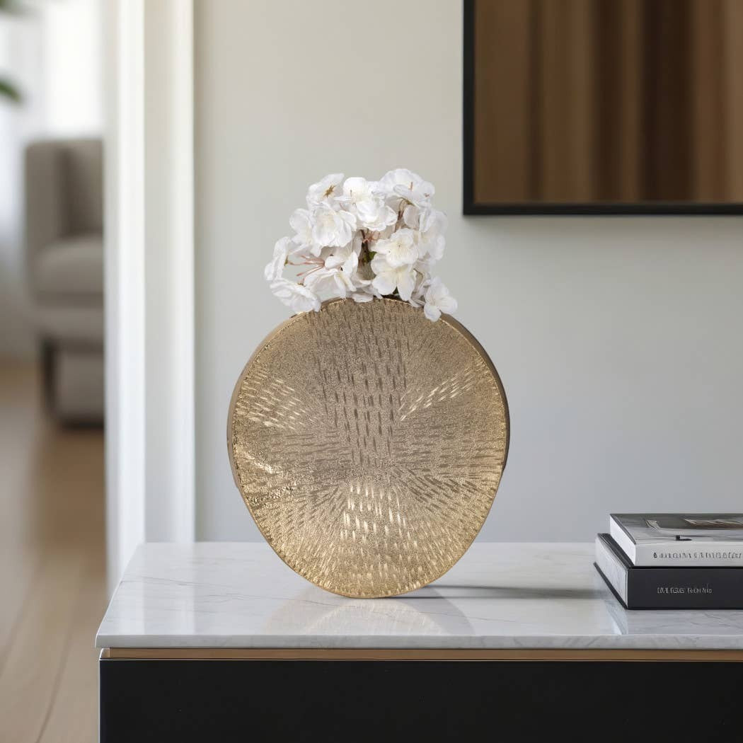 Chic Collective gold metal etched oval decorative vase with white flowers on a marble table.