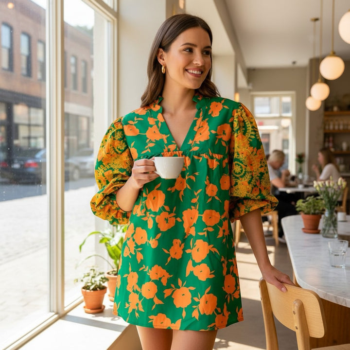Chic Collective green and yellow floral print mini dress with puff sleeves and V-neck. Model holds a white cup.
