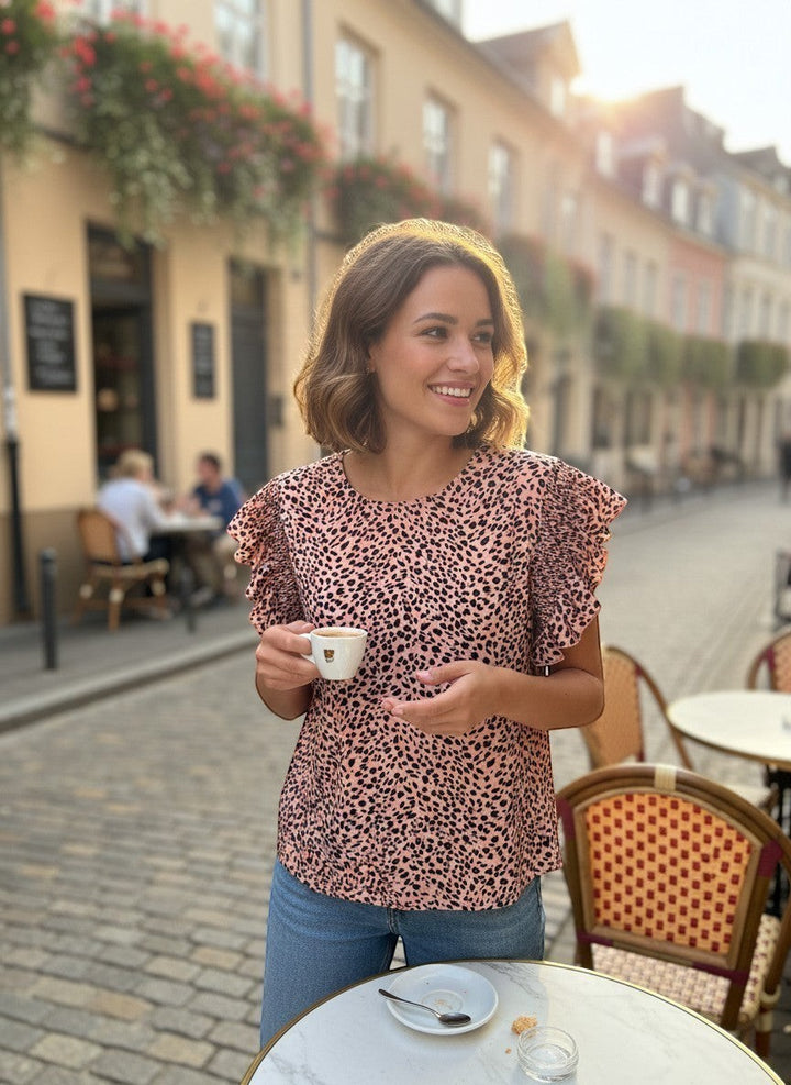 Chic Collective mauve and black leopard print top with ruffle sleeves, worn by a woman at an outdoor cafe.