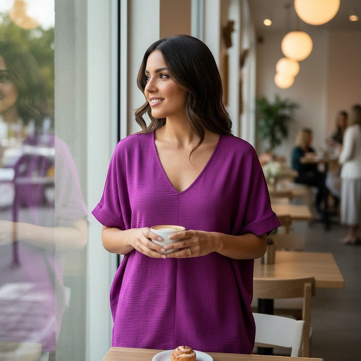 Chic Collective light plum woven dolman top with V-neck and short sleeves, worn by a woman holding a coffee cup.