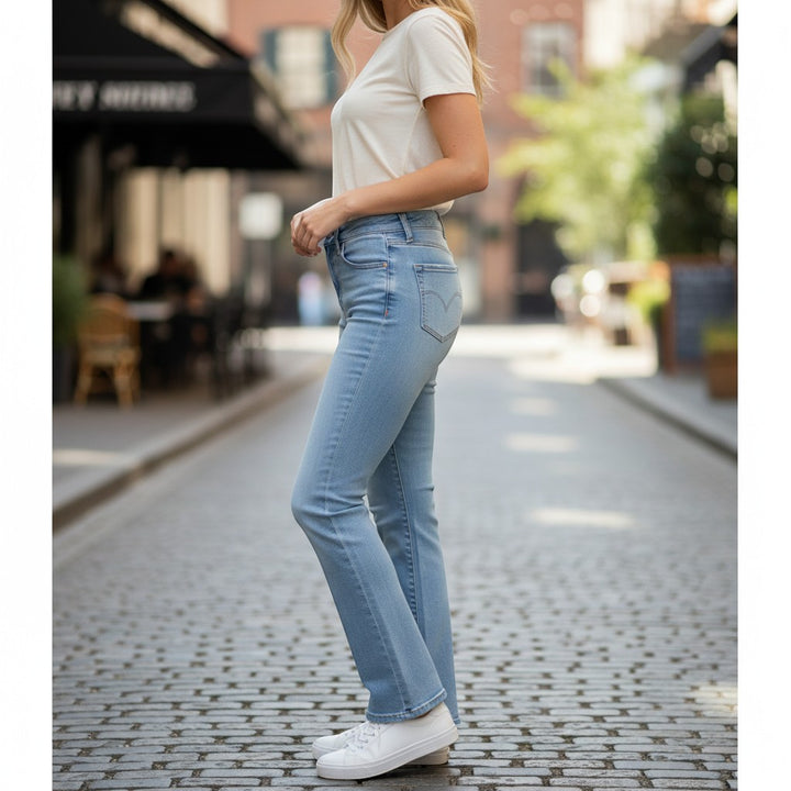 Chic Collective Risen Mid Rise light wash denim jeans with frayed hem, worn by a woman on a cobblestone street.