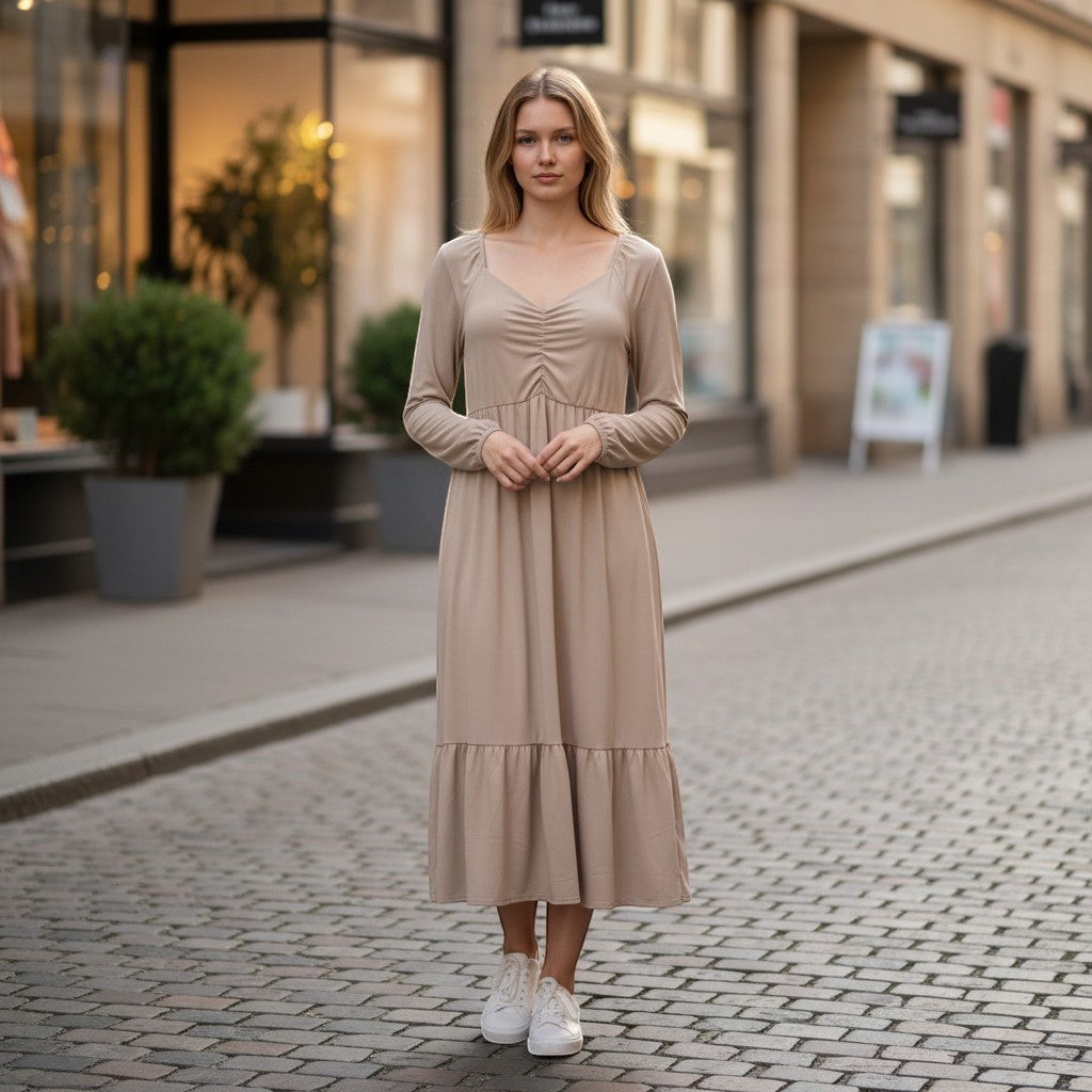 Chic Collective mauve ruched maxi dress with long sleeves and tiered hem, worn by a woman on a cobblestone street.