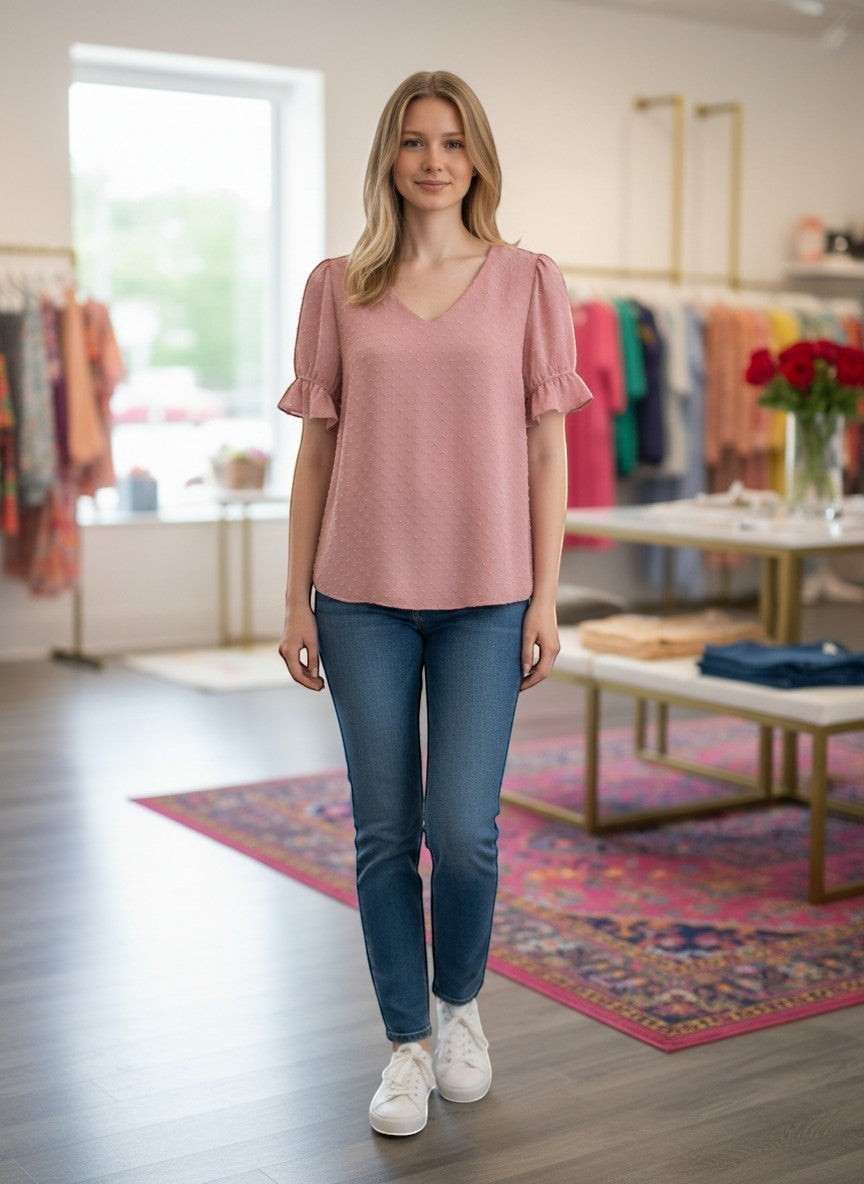 Chic Collective mauve Swiss dot v-neck top with ruffled short sleeves, paired with blue jeans and white sneakers.