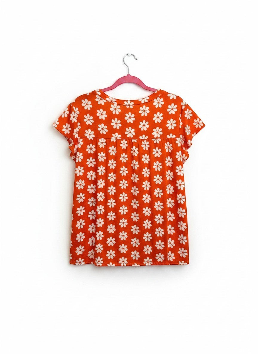 Chic Collective orange babydoll top with white daisy print and flutter sleeves.