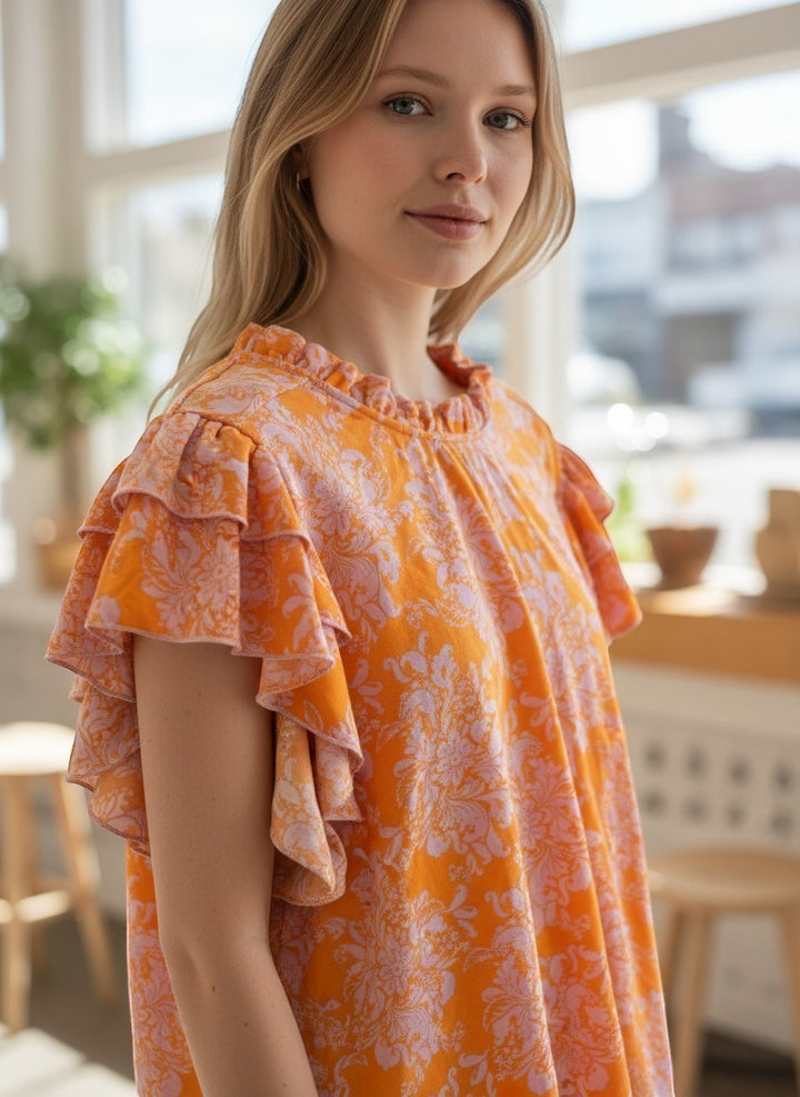 Chic Collective orange lilac floral mock neck double layered ruffle top on a woman.