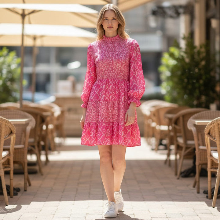 Chic Collective pink and white patterned long sleeve tiered mini dress with a smocked bodice and mock neck.