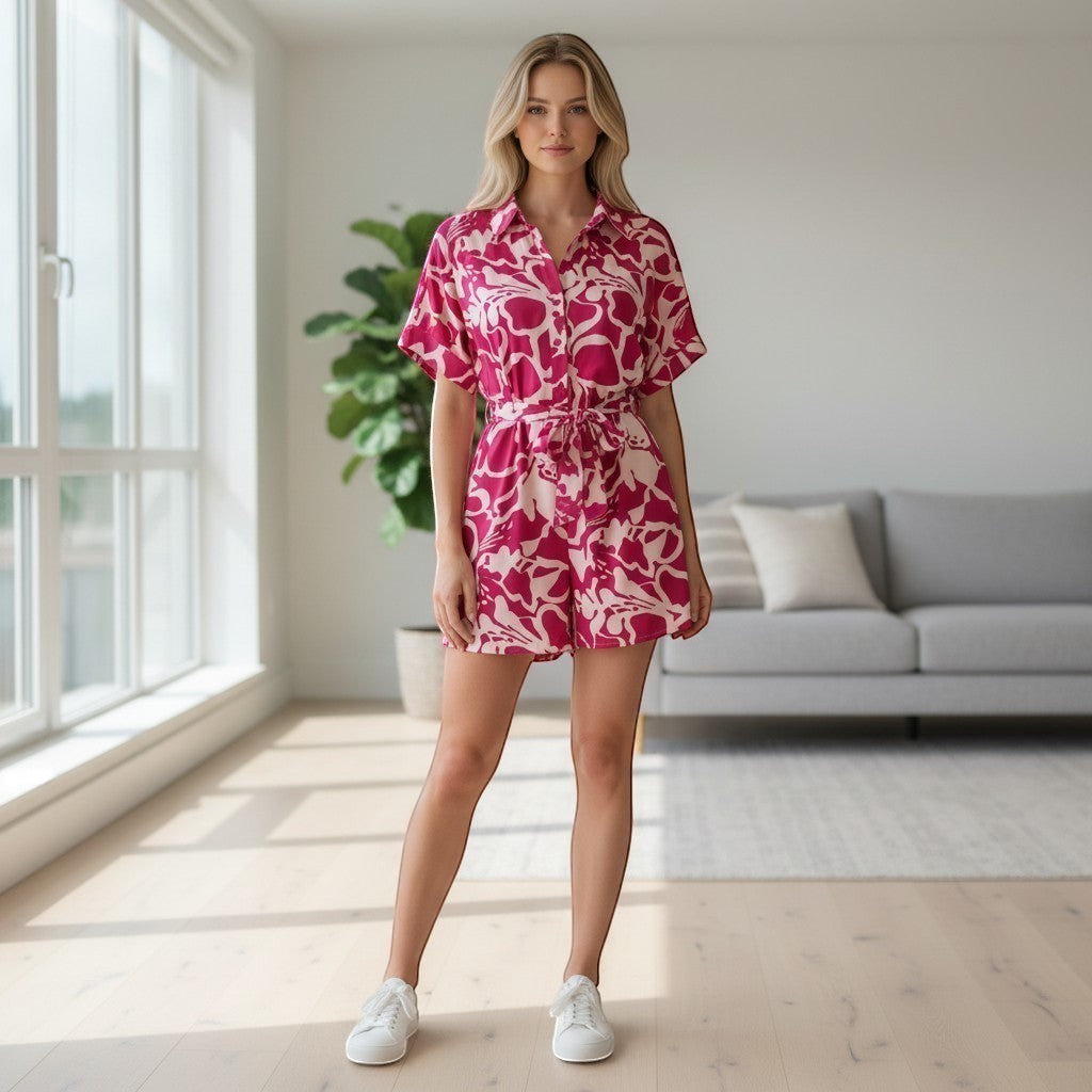 Chic Collective pink and white abstract print short romper with tie waist and collared neckline worn by a woman indoors.