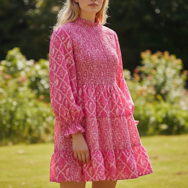 Chic Collective pink and white patterned smocked mini dress with tiered skirt and long sleeves.