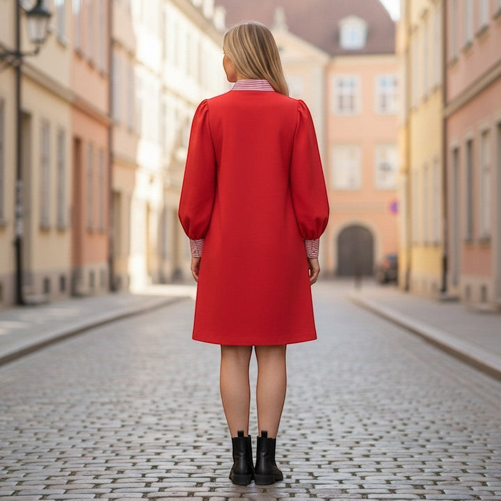 Chic Collective red dress with puffed sleeves and red/white striped collar and cuffs, worn by a woman on a cobblestone street.