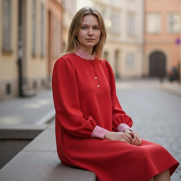 Chic Collective red dress with red and white striped collar and cuffs, long puff sleeves, and button detail. Model sitting outdoors.