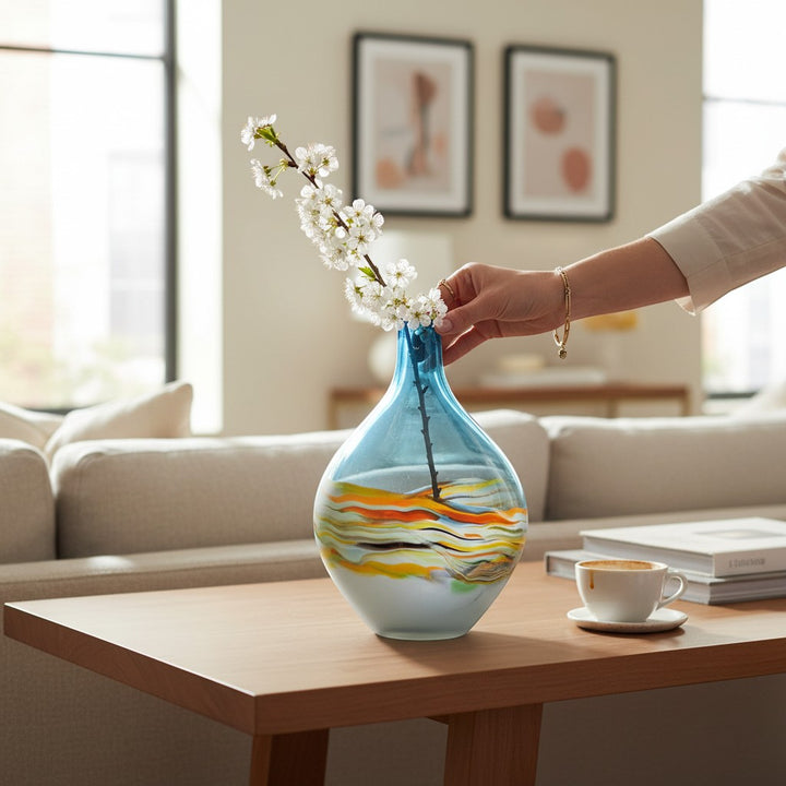 Chic Collective Rhian hand-blown glass vase with blue neck and swirling agate pattern base, holding a branch with white flowers.