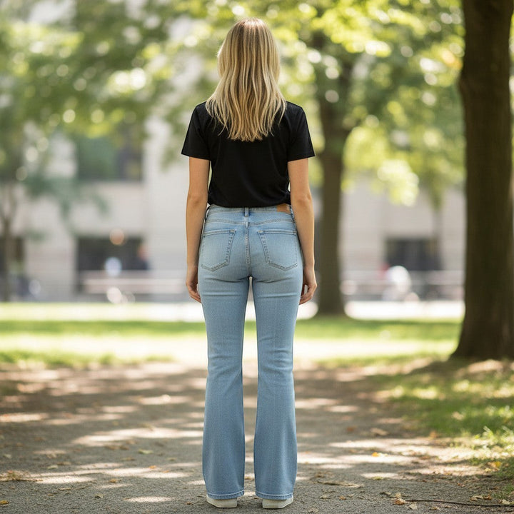 Chic Collective Risen Mid Rise Frayed light wash denim flare jeans, size 15. Model from behind.